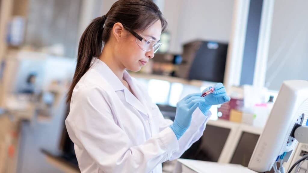 laboratory technician preparing a test tube sample for analysis with a chemistry analyzer