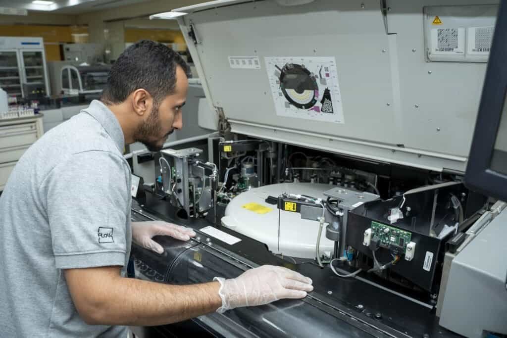 Laboratory technician performing routine maintenance on a clinical chemistry analyzer to ensure accurate diagnostic test results.
